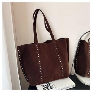 Detailed view of brown suede tote bag featuring silver rivet accents and spacious interior
