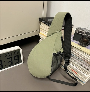 Light green water-drop crossbody bag with mesh side pockets on a desk background