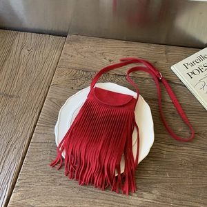 Detail shot of red suede crossbody bag with long fringes and adjustable strap