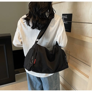 Detail of black waterproof nylon sports bag with side zipper pocket and brand woven label