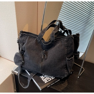Detail of a black washed denim tote bag with side pockets and a small round coin purse