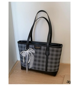 Detail of checkered tote bag with lace bow, pearl charm and leather brand tag