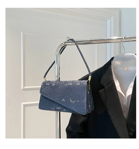 Detailed macro shot of the dark blue snakeskin texture and asymmetric flap of the bag