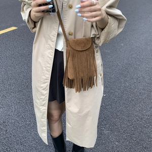 Brown suede crossbody bag with long tassels shown on beige trench coat model