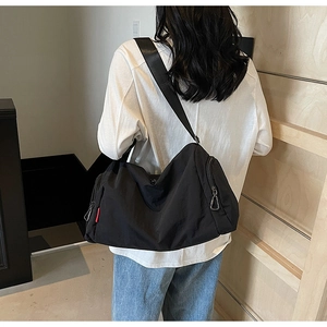 Detail view of large black canvas crossbody bag showing spacious nylon material and strap