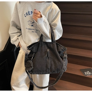 Detail of black washed denim tote bag with round coin purse and adjustable strap on wood