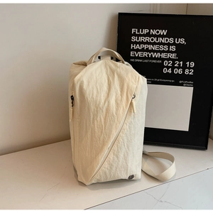 Detail of off-white nylon backpack featuring unique geometric folds and side zipper