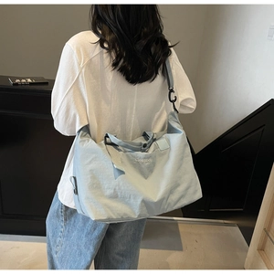 Close-up of the light blue travel bag with adjustable strap and brand logo detail