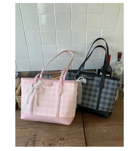 Close-up of pink and black plaid tote bags with lace bows and pearl charms on wood