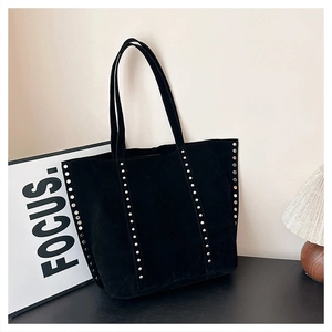 Detailed view of black suede tote bag with silver metal studs and long handles