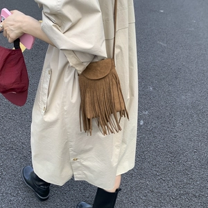 Detail of brown faux suede crossbody bag featuring long bohemian tassels and fringe