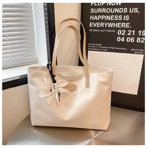 Close-up of off-white leather tote bag with elegant floral charm and slim straps