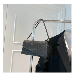 Detailed view of a black snake-texture shoulder bag hanging on a silver hanger