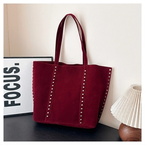 Detail view of burgundy suede tote bag with silver studs in a minimalist interior setting