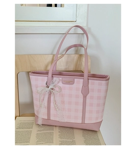 Detailed shot of pink plaid tote bag featuring lace bow and pearl charms on a chair