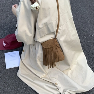 Outdoor shot of a brown fringe crossbody bag in frosted suede with bohemian tassels