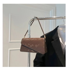Close-up of brown snakeskin crossbody bag hanging on a rack with a black blazer