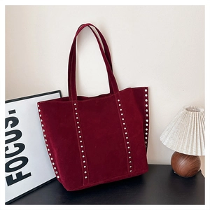 Detail of burgundy suede tote bag featuring vertical silver rivet studs and retro style