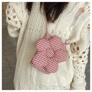 Détail d'un sac bandoulière en forme de fleur à carreaux rouges et blancs avec sangle