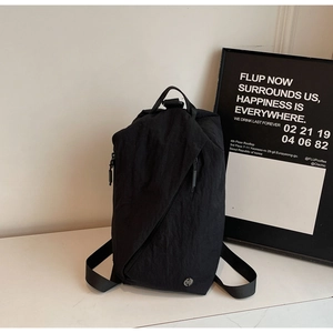 Detail of black multi-functional canvas backpack with asymmetric zippers on marble surface