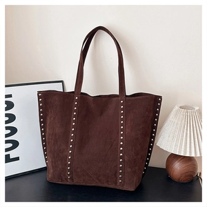 Detail of dark brown suede tote bag featuring vertical silver stud accents in a lifestyle setting