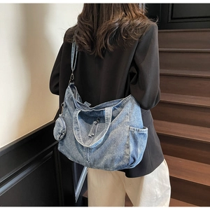 Fashionable denim tote bag with adjustable strap and small coin purse shown on model