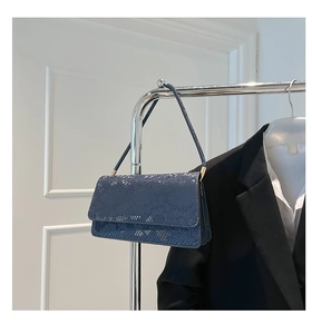 Detail of blue snake pattern shoulder bag hanging next to a chic black blazer
