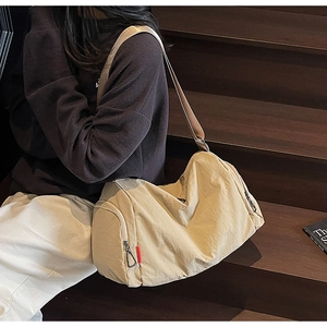 Detail view of large capacity beige travel bag showing wide shoulder strap and side zipper