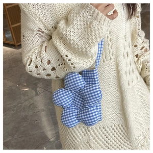 Détail d'un petit sac bandoulière à fleurs à carreaux bleus et blancs sur pull beige