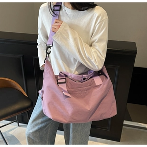 Purple large capacity travel bag worn crossbody, showing nylon material and brand tag