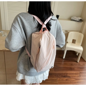 Detail of pink nylon backpack featuring light crinkle texture and side zipper pocket