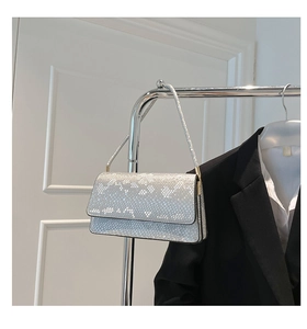 Detail of silver snake skin texture leather handbag with glossy gold metal hardware