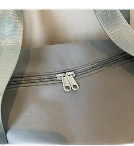 Detail of dual smooth zippers and durable wide woven strap on the grey-blue sports bag