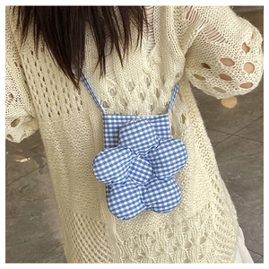 Détail du petit sac à bandoulière en forme de fleur à carreaux bleus sur un haut