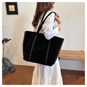 Detail view of large black rivet tote bag showing suede texture and metal stud accents