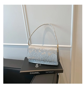 Close-up of metallic snakeskin texture on silver shoulder bag over decorative book