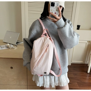 Detail showing pink waterproof nylon crossbody bag with diagonal zipper and webbing strap