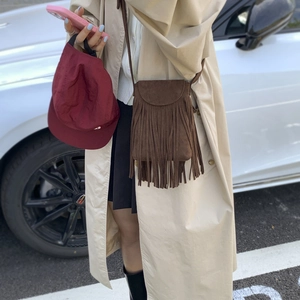Detailed outdoor shot of a brown fringe crossbody bag with retro suede texture
