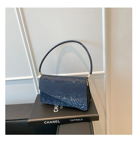 Detailed close-up of dark blue snakeskin pattern texture on the fashion shoulder bag
