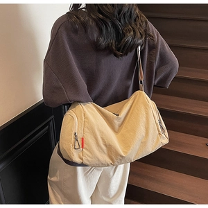 Lifestyle view of a large beige sports bag with side zipper and shoulder strap