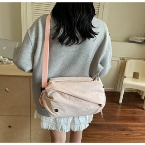 Detailed view of light pink nylon crossbody bag with adjustable wide strap and texture