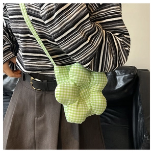 Vue portée d'un sac bandoulière en forme de fleur à carreaux verts et blancs