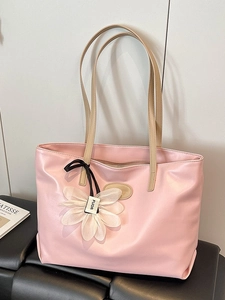 Pink faux leather tote bag with elegant daisy charm accessory and beige shoulder straps
