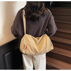 Close-up of beige half-moon gym bag with adjustable strap and side zipper detail