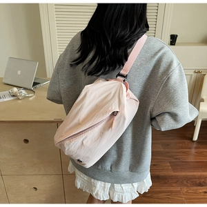 Rear view of a model wearing a pink nylon crossbody bag in a minimalist interior setting
