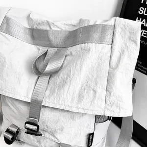 Detail van grijze nylon tas met geplooide textuur, merklabels en zijvak van mesh-materiaal