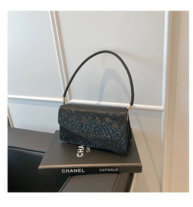 Close-up of black snakeskin texture flap handbag with elegant gold hardware and handle