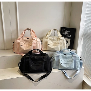 Large travel duffel bags in pink, beige, black, and blue with adjustable shoulder straps