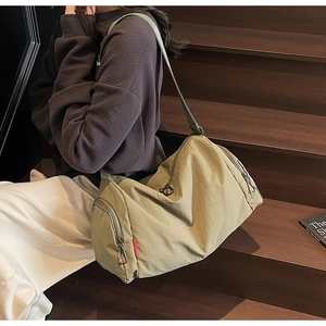 Detail of light olive nylon sports bag showing metal zippers and red label on staircase