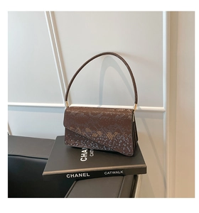 Close-up of brown snakeskin pattern faux leather bag with unique asymmetrical flap design